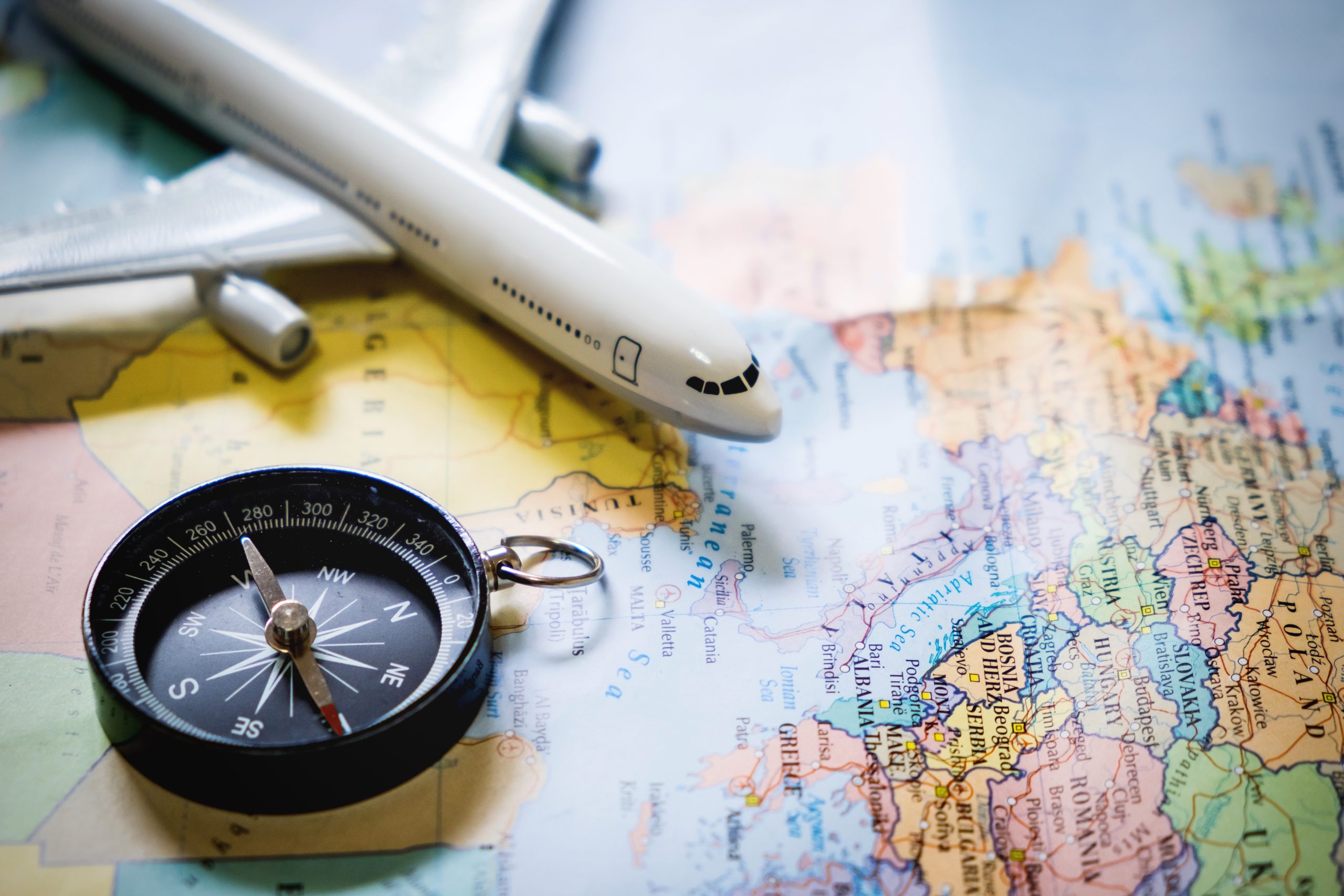 selective focus of miniature tourist on compass over map with pl